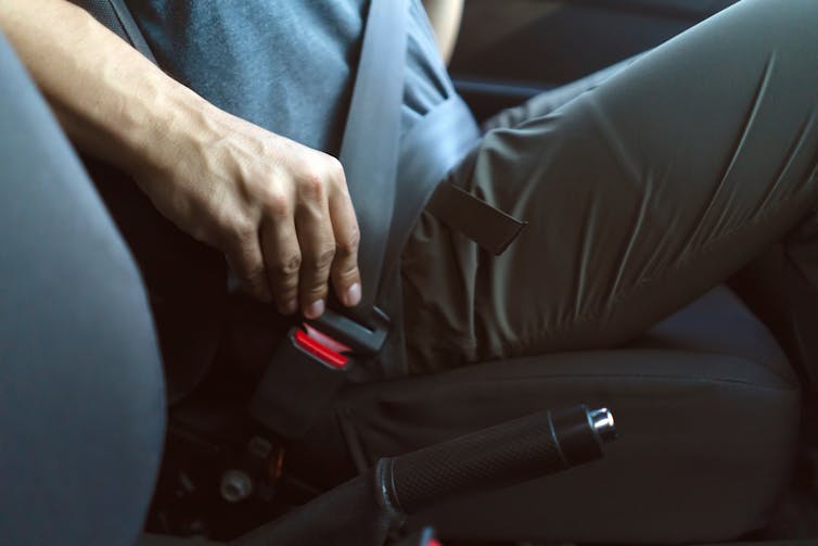 A male hand on a car seatbelt