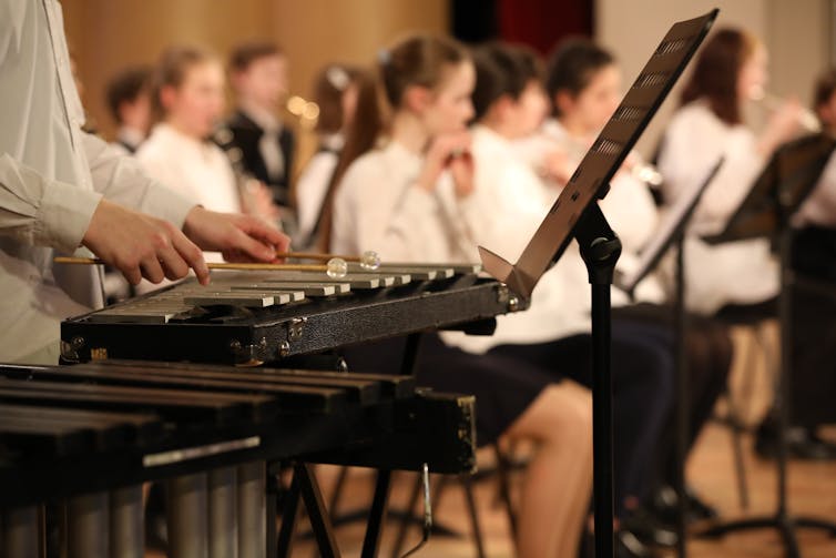 Young people play musical instruments in an orchestra.