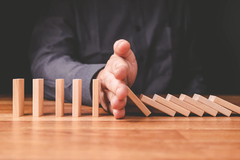 des dominos qui toment arrêtés par une main pour signifier la possibilité de stoper le fameux effet domino