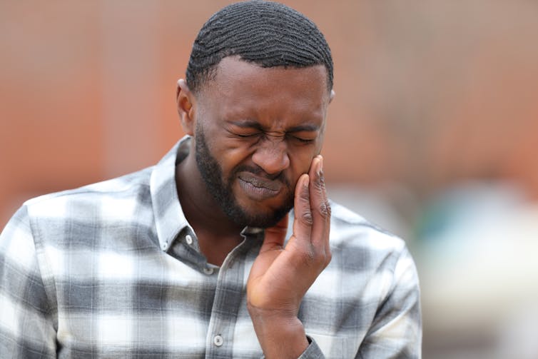 A man holds the side of his jaw in pain.