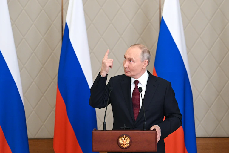 Russian president, Vladimiar Putin, stands at a podium pointing upwards, November 2024.