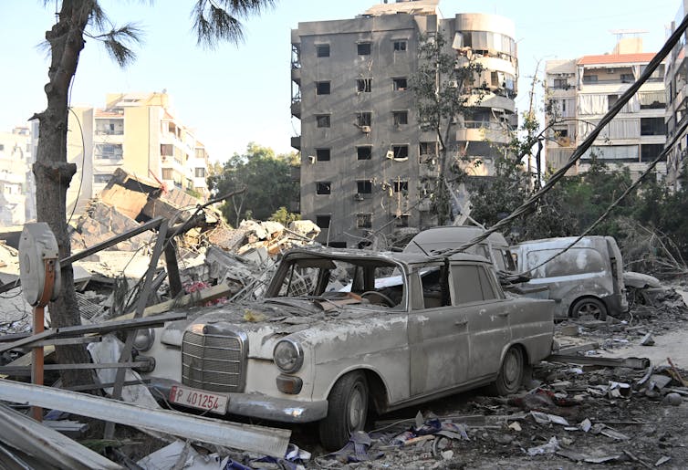 A destroyed car is seem among rubble.