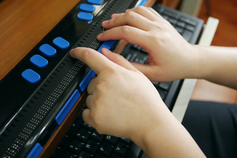 Personne tapant sur un clavier numérique en braille pour malvoyants ou non-voyants