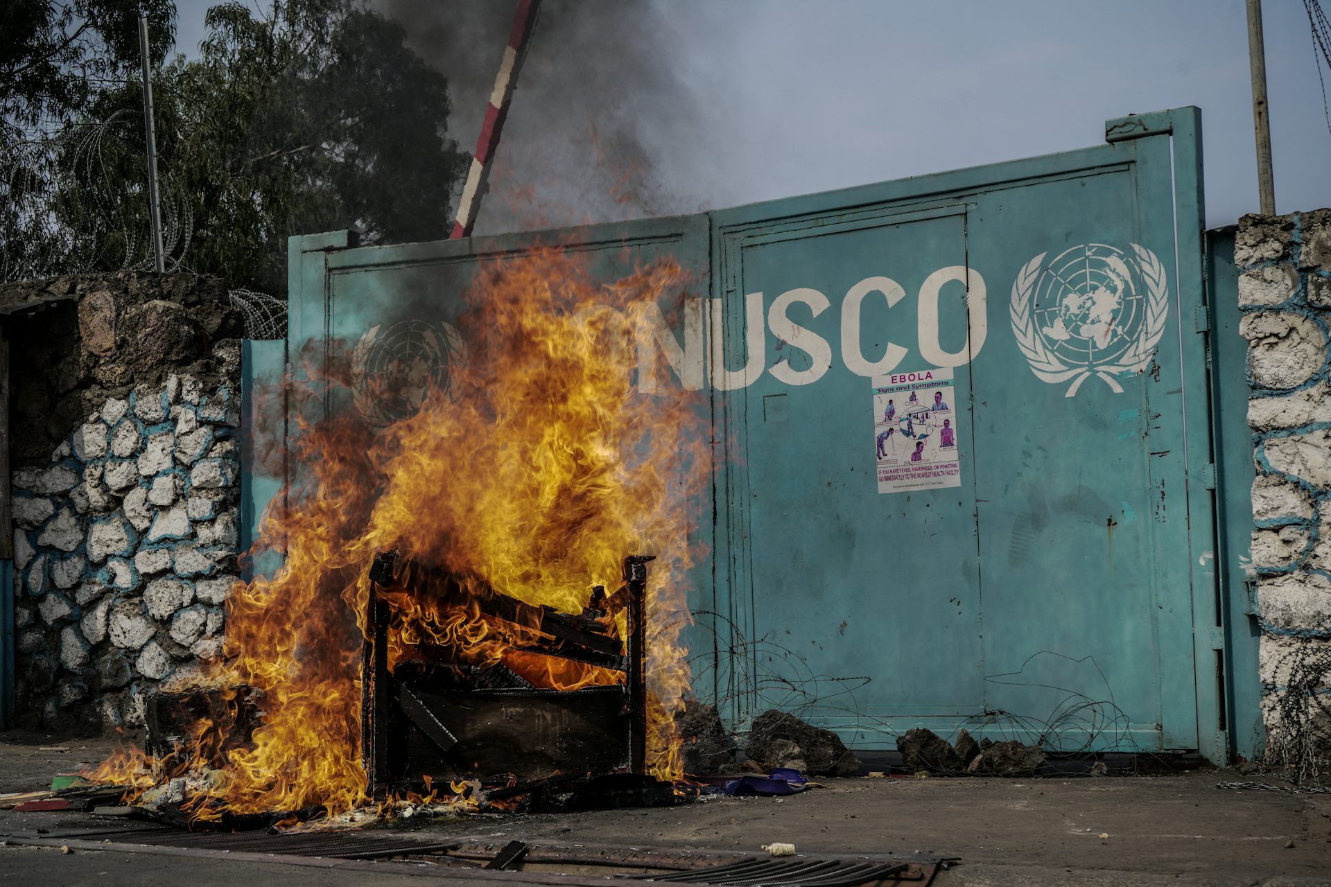 Départ de feu devant un portail sur lequel se trouve le sigle de l'ONU et l'inscription "MONUSCO"