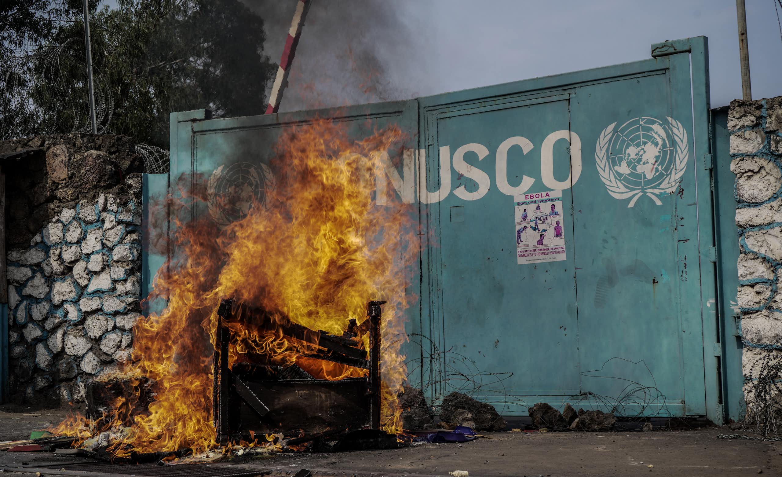 Départ de feu devant un portail sur lequel se trouve le sigle de l'ONU et l'inscription "MONUSCO"