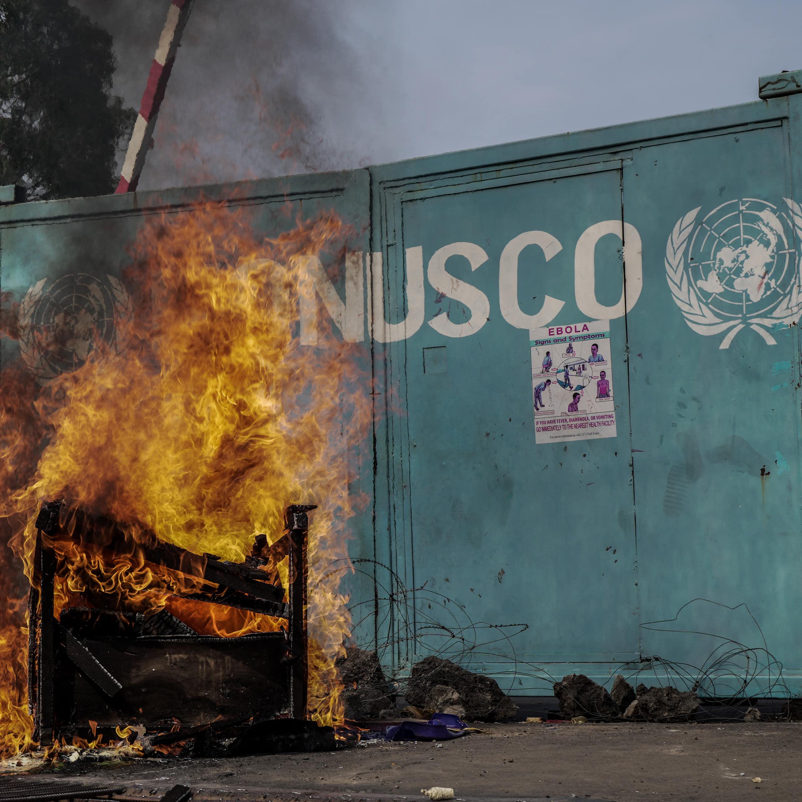 Départ de feu devant un portail sur lequel se trouve le sigle de l'ONU et l'inscription "MONUSCO"