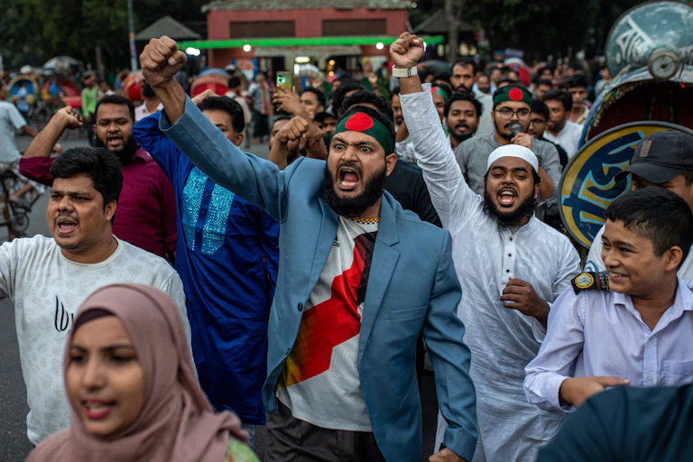 Men with raised fists march down a street.