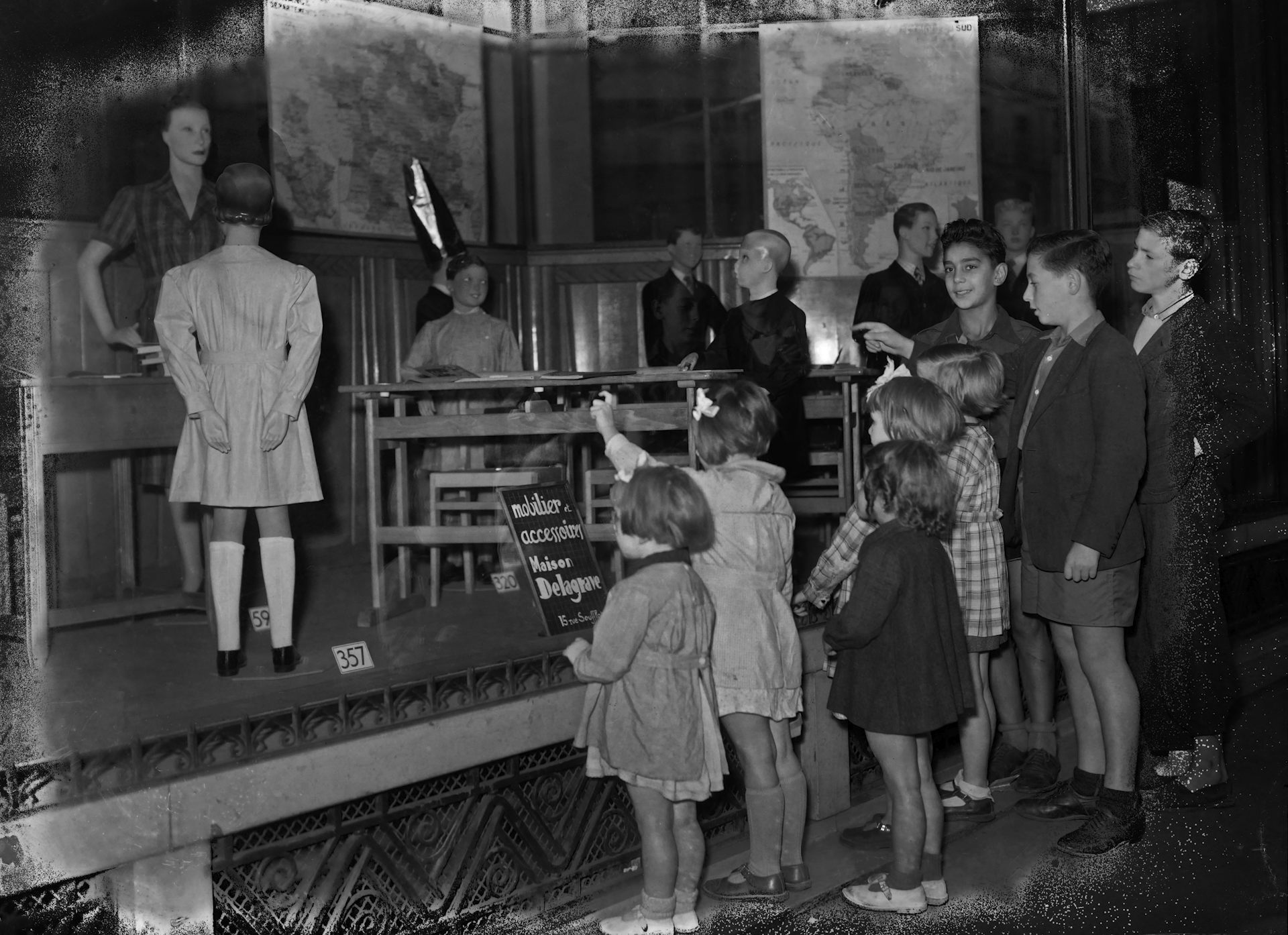 Children look at a window displaying a classroom in a department store, a few days before the start of the 1947 school year, in Paris