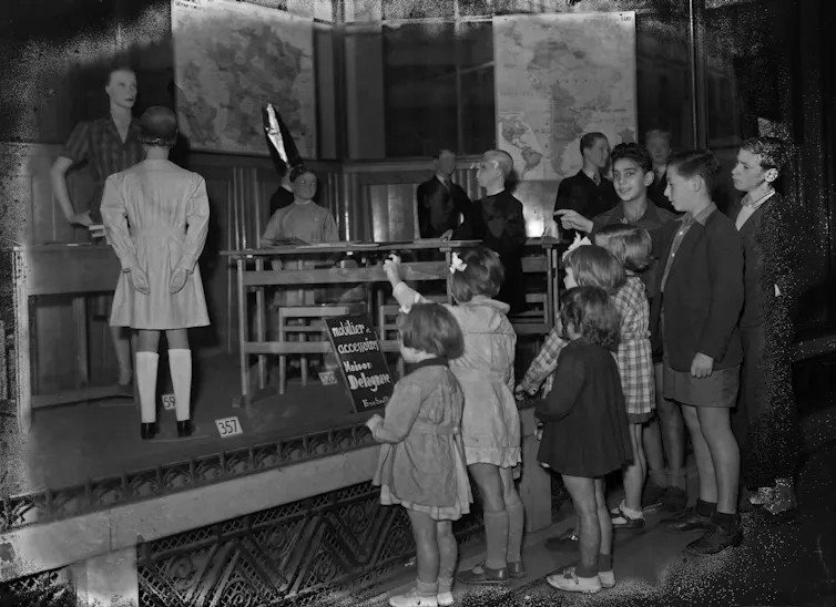 Children look at a window displaying a classroom in a department store, a few days before the start of the 1947 school year, in Paris
