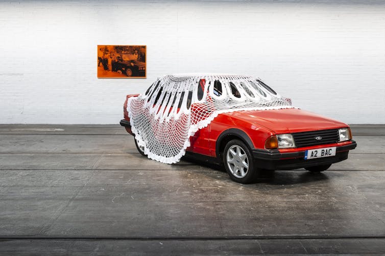 A red Ford Escort draped in a huge lace doily.