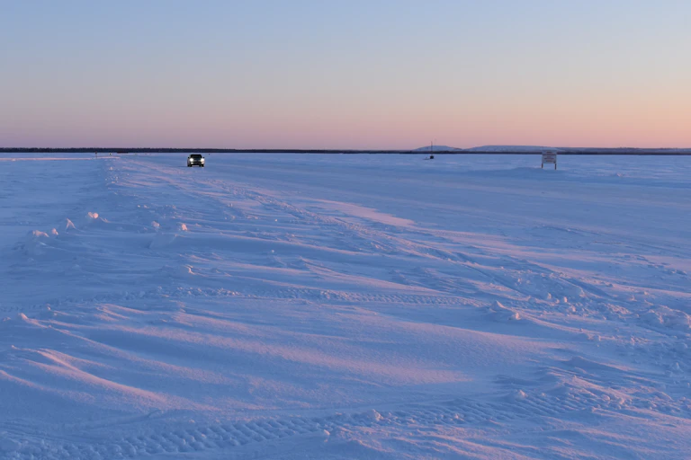 A car drives across an ice road.