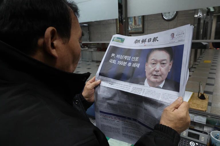 Um homem sul-coreano lê um jornal com uma foto do presidente Yoon Suk Yeol na primeira página.