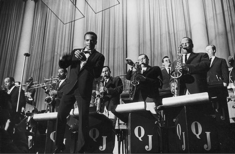 Black-and-white image of a big brass band fronted by a suit-wearing young Jones