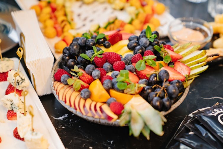A plate of chopped fruit on the table with other food