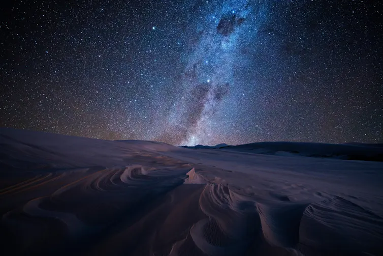 Bright stars shining above sand dunes.