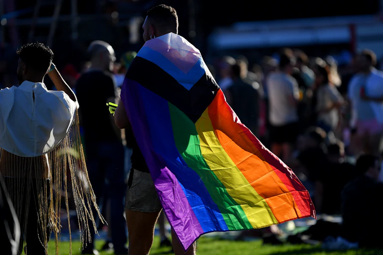 Person wearing rainbow flag cape