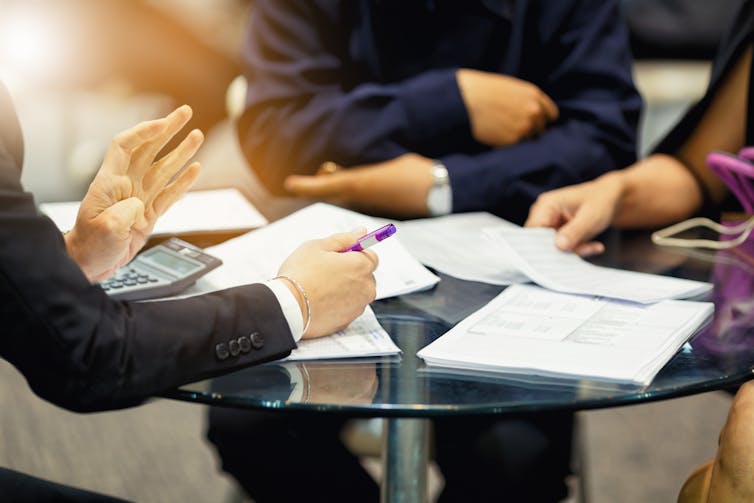 People wearing suits in a meeting around a table