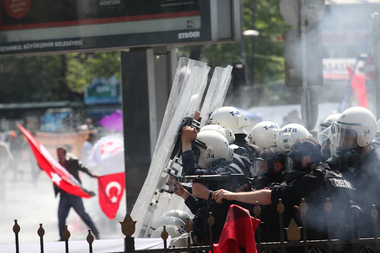 Turkish riot police clash with protesters holding Turkish flags.