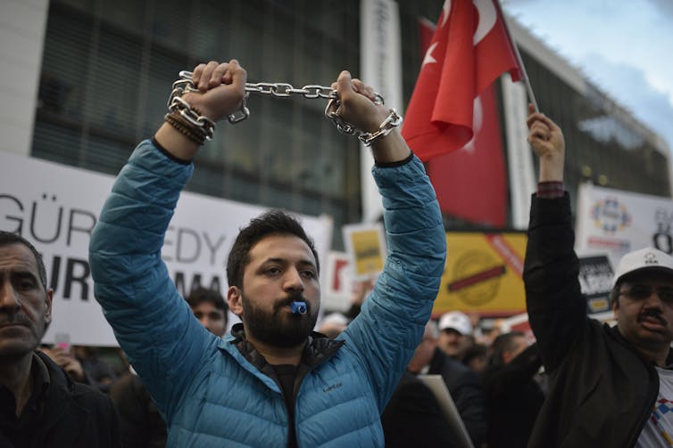 A man at a protest holding a chain in the air.