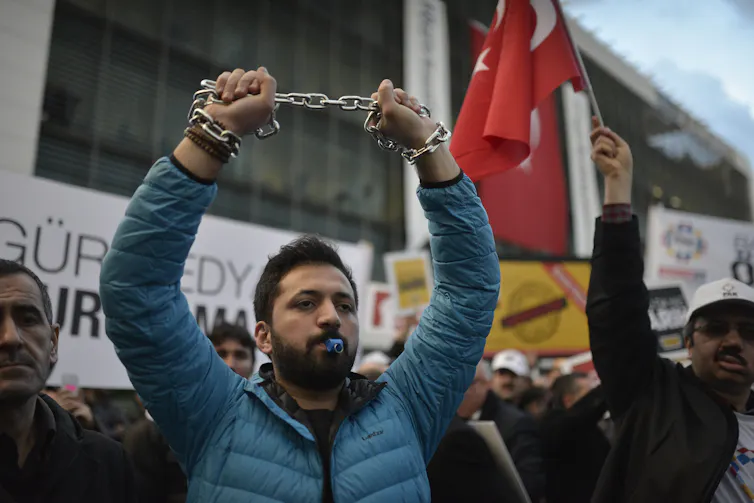 A man at a protest holding a chain in the air.