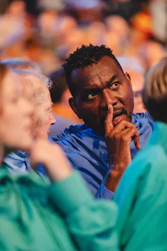 A man in blue robes concentrates on what's in front of him.