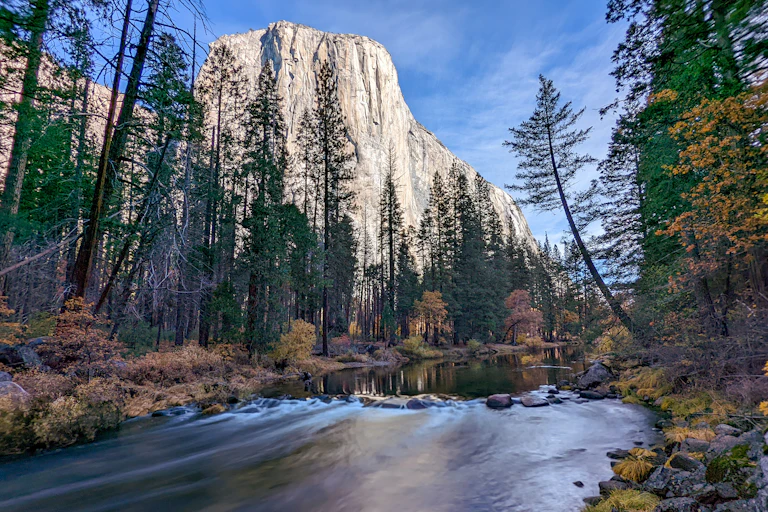 White cliffs tower over a river bordered by evergreen trees