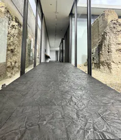A corridor with grey, irregular metal floor tiles