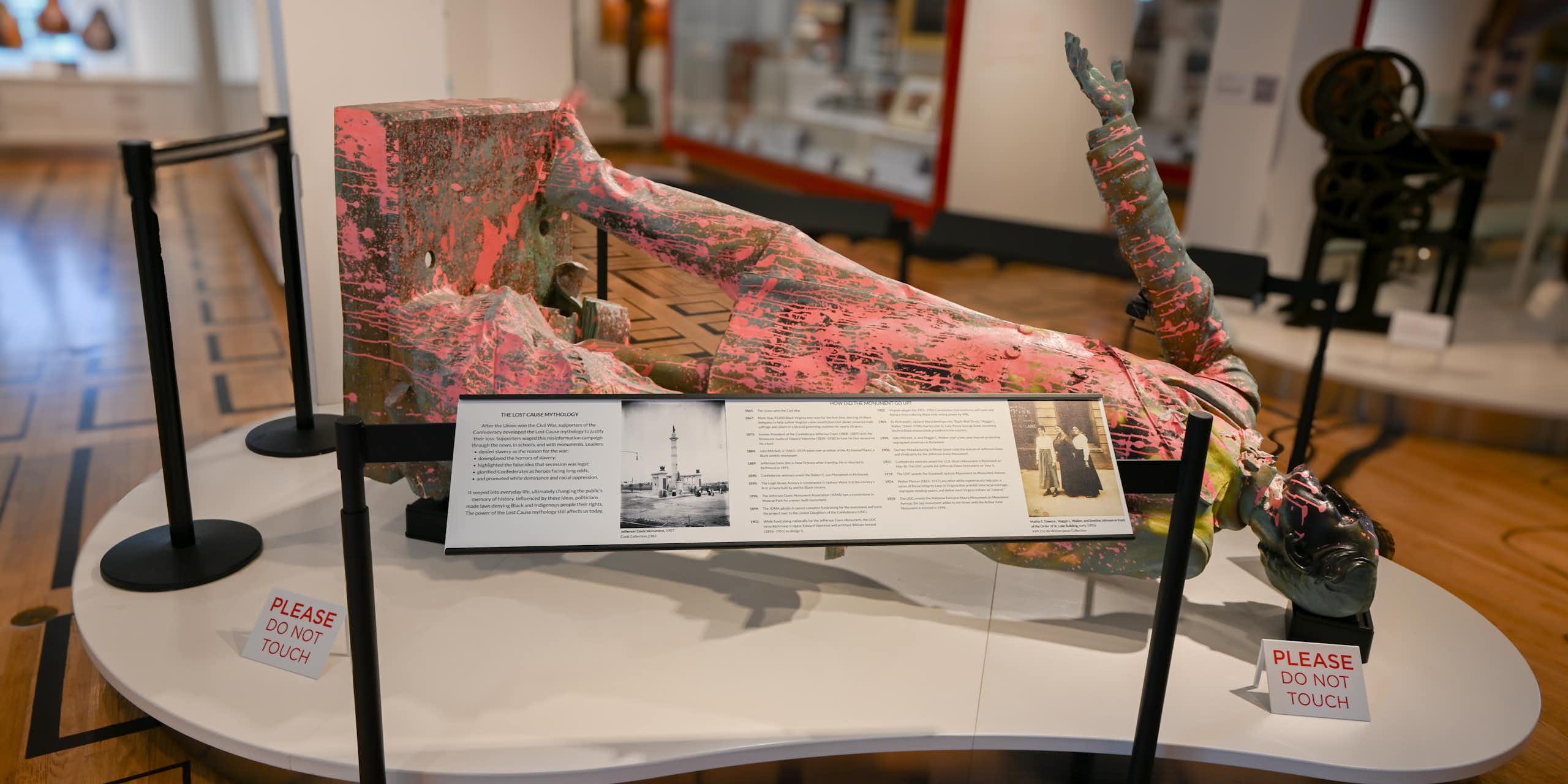 Pink paint-spattered bronze statue lies on its back on a display table