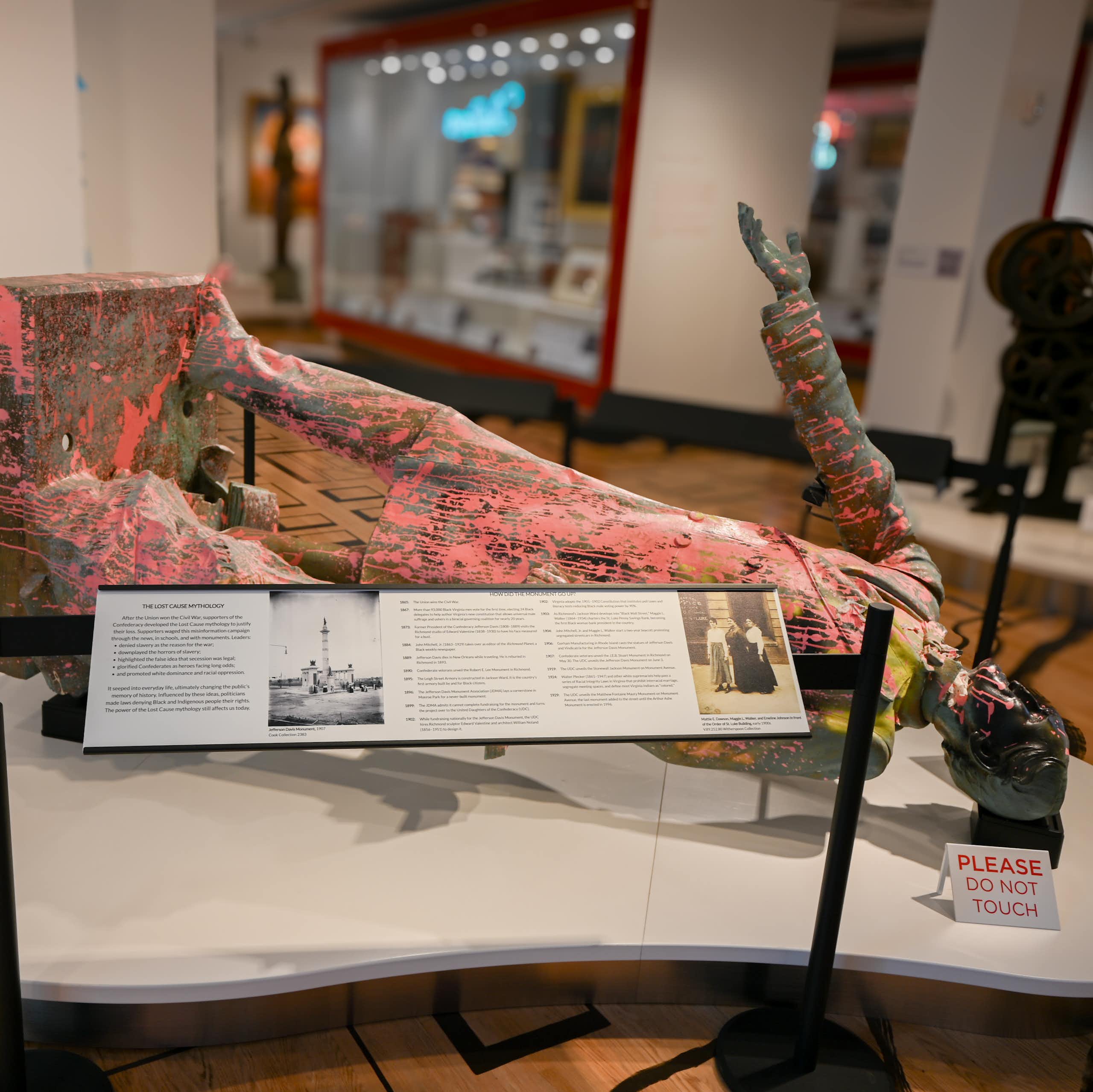 Pink paint-spattered bronze statue lies on its back on a display table