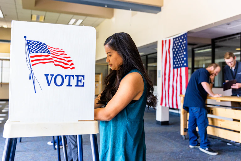 Woman stands at voting booth.