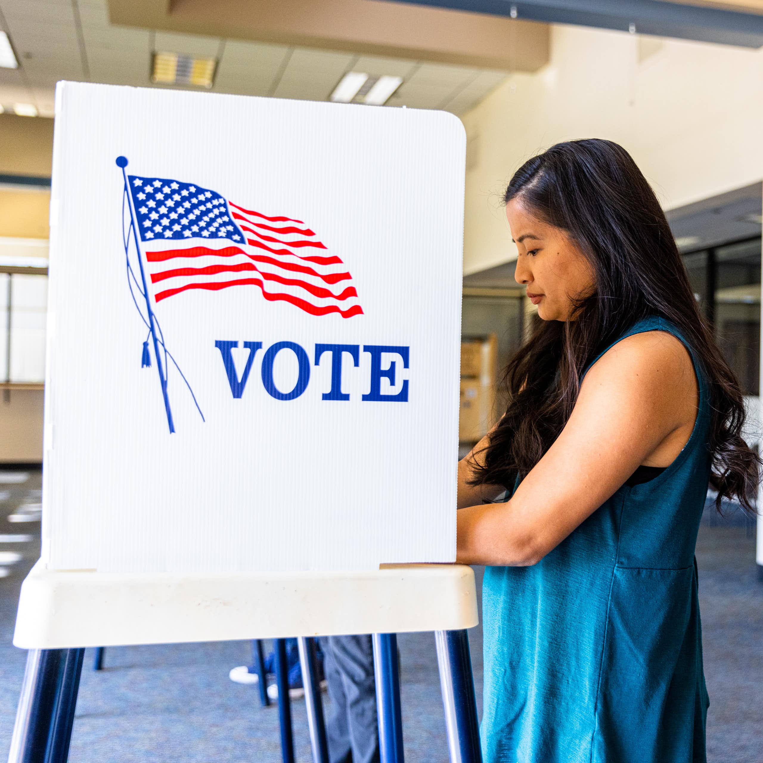 Woman stands at voting booth.