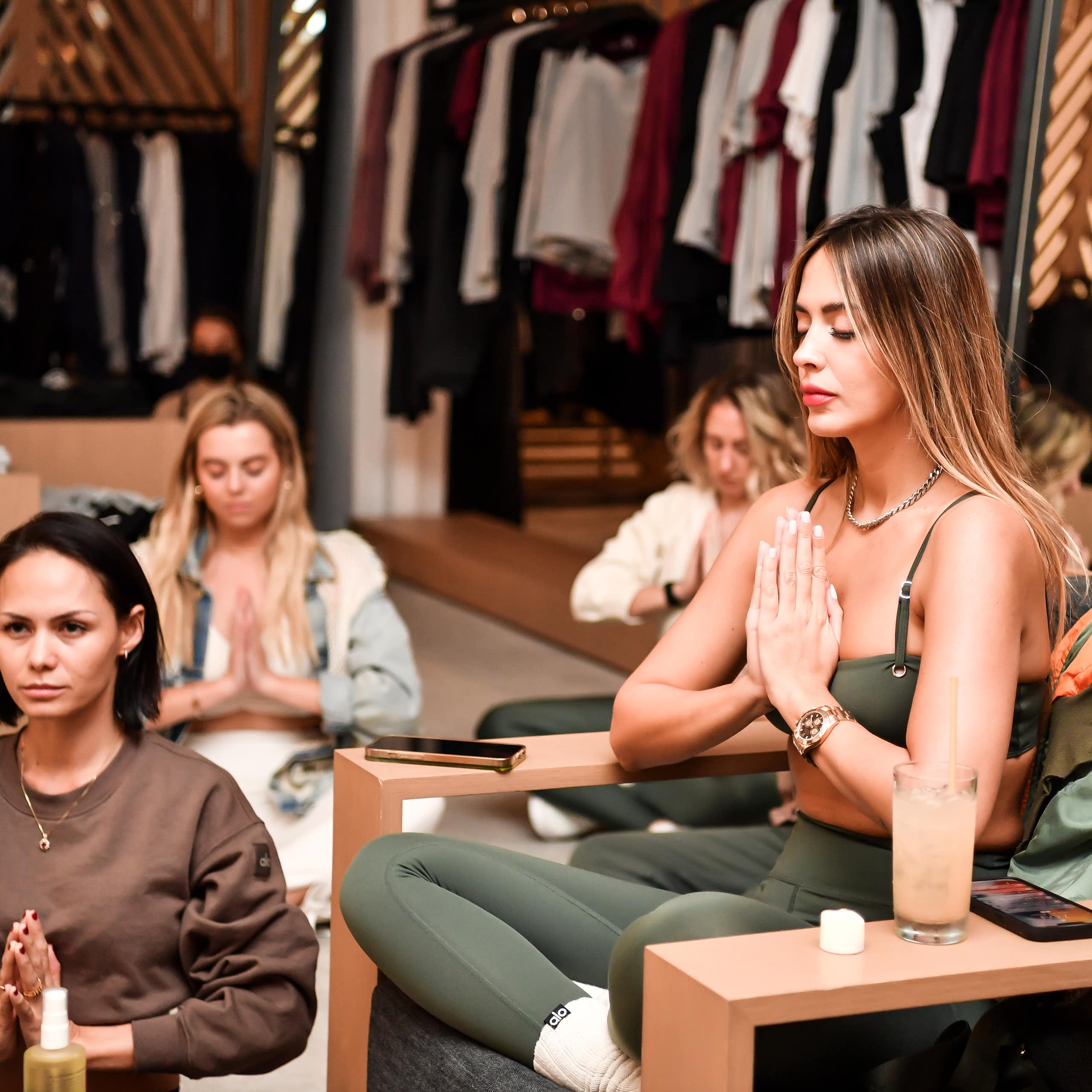 Four women in a meditative pose with their hands folded in a 'namaste.'