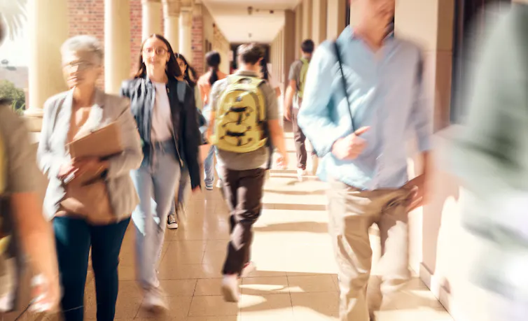 Blurred photo of people carrying books and backpacks walking