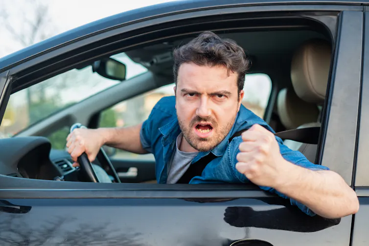 A man gestures angrily at another driver.