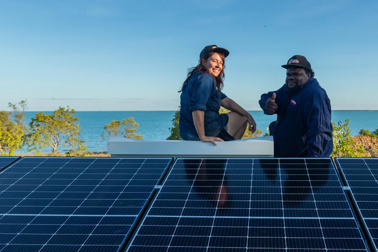 woman and man sit on roof near solar panels