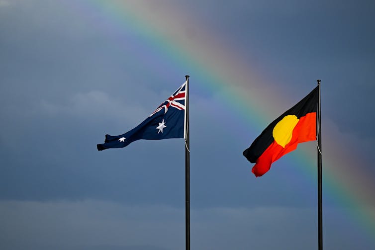 Australian and Aboriginal flags in front of a rainbow