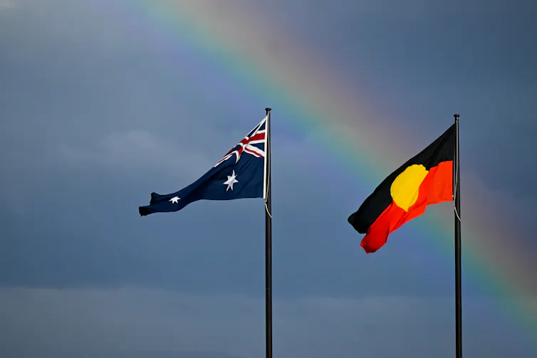 Australian and Aboriginal flags in front of a rainbow