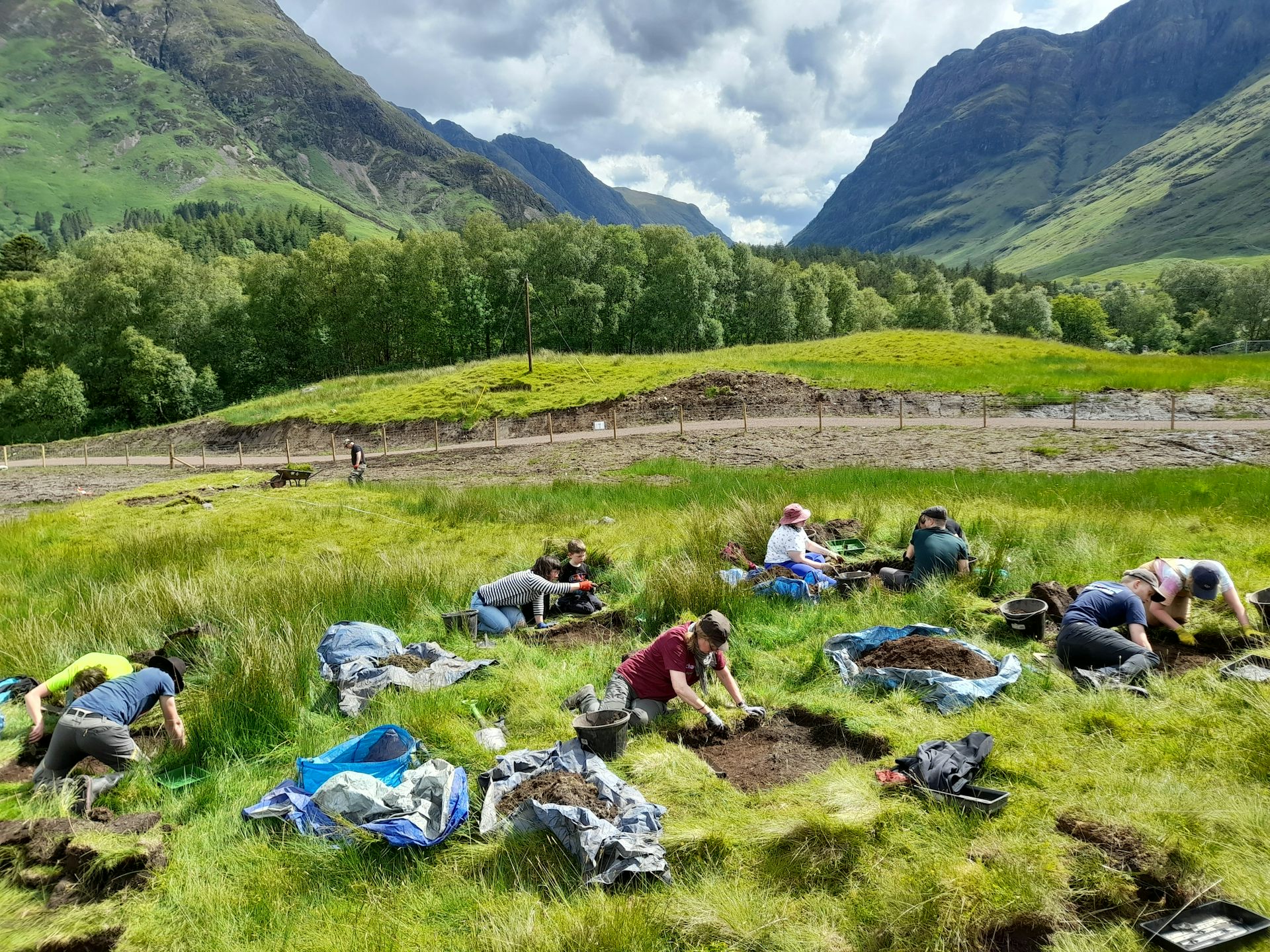A group of archaelogists on their hands and knees excavating artefacts.