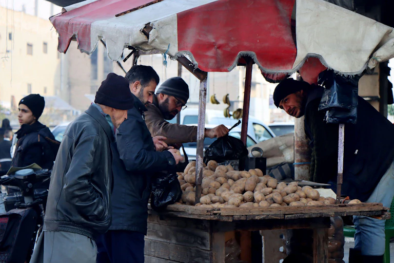People shop for potatoes at a market.