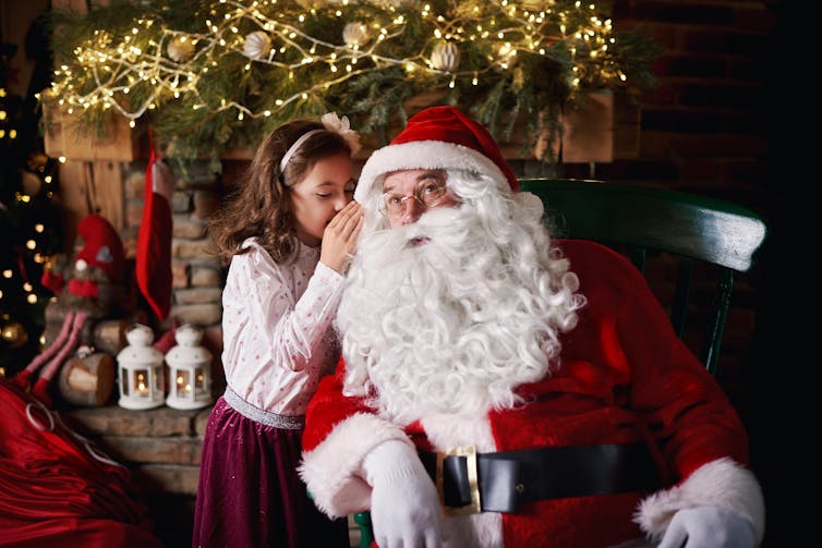 Girl whispering in Santa's ear