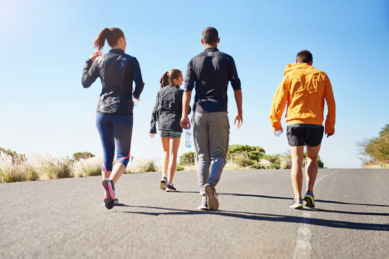 Four people go for a walk on a road outdoors.