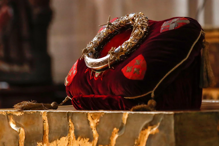 A golden crown atop a red velvet cushion.
