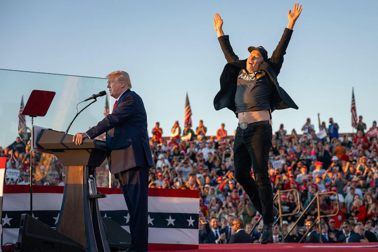 Donald Trump with Elon Musk behind him with arms in the air.