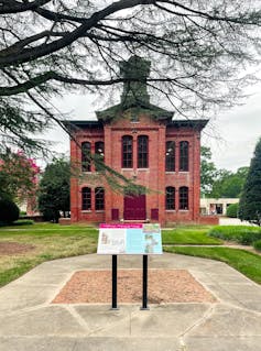 Photo of an old red-brick courthouse and a plaque