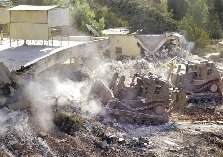 a bulldozer rides over dust and rubble