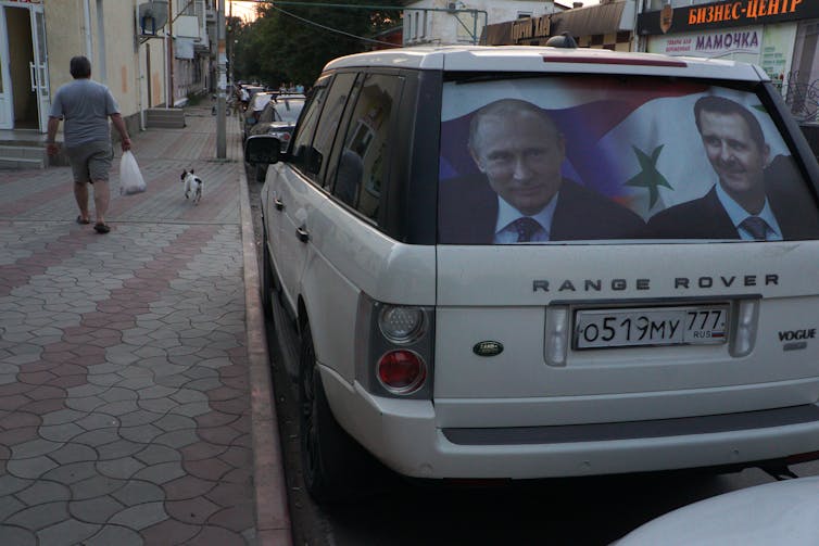 A car has a picture of two men in the rear window.