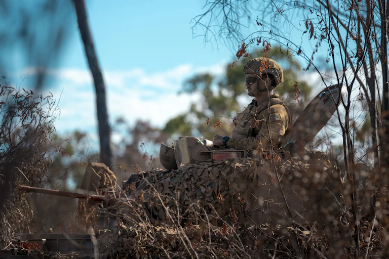 A soldier in camouflage gear in a tank in the bush