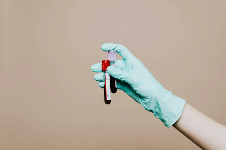 A gloved hand holding up two vials of blood.