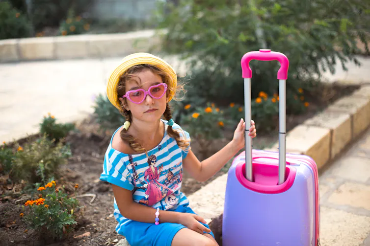 A glum little girl with a suitcase.