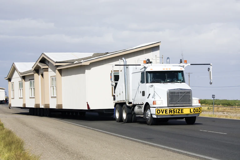 A truck transports a house down a road